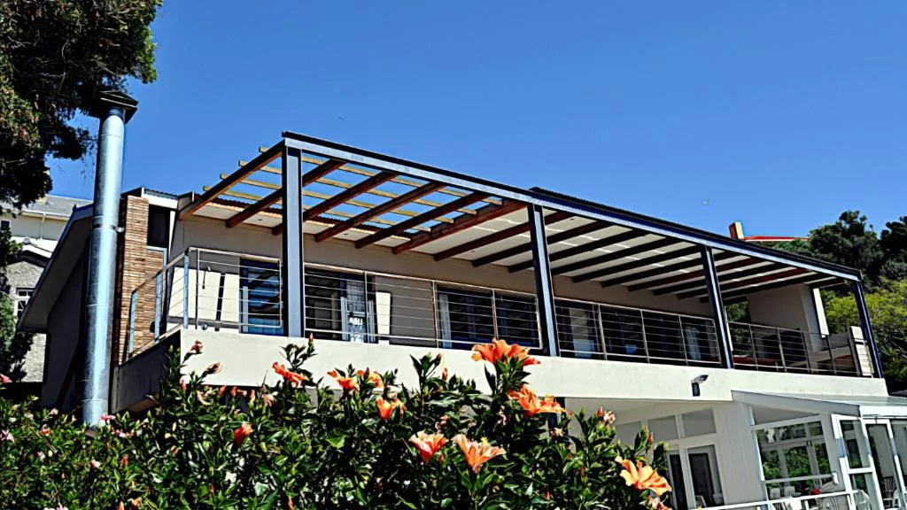 Modern white apartment building with pergola deck and flowering garden beds