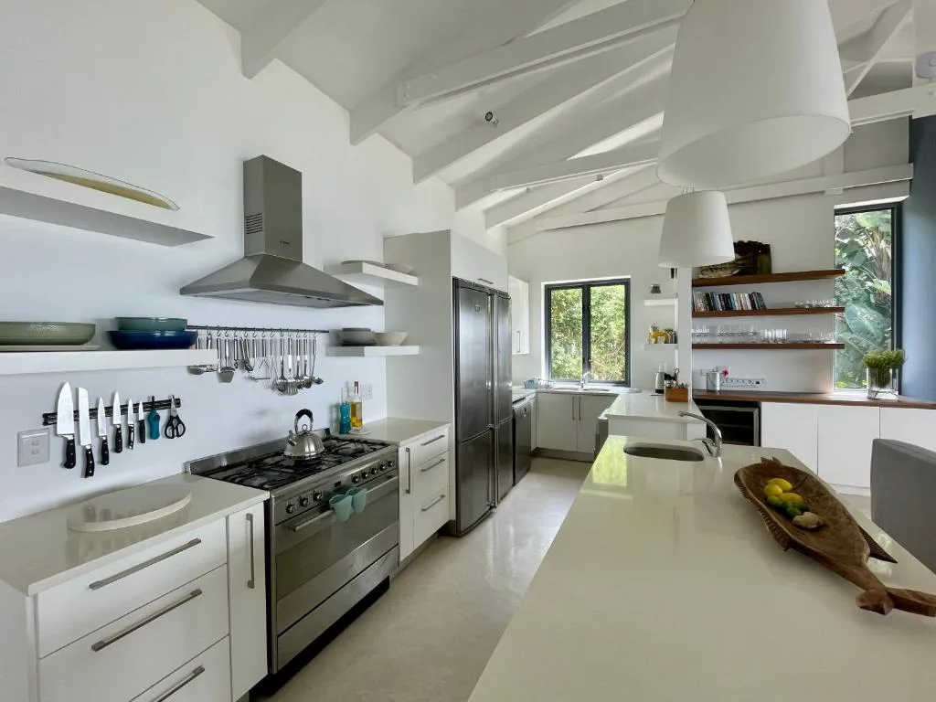 Modern kitchen with stove, refrigerator, white cabinetry and island counter