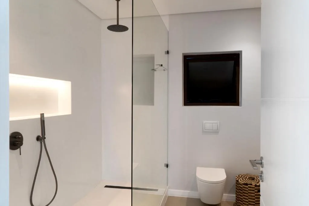 Modern bathroom with walk-in shower, toilet, and illuminated mirror