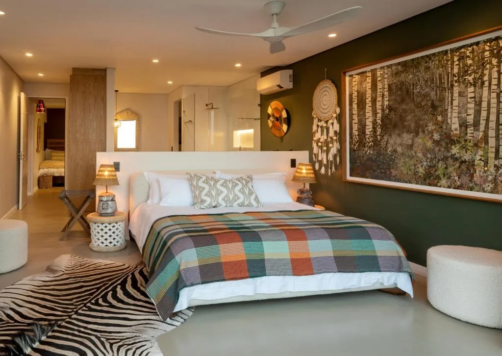 Modern bedroom with plush bed, accent wall, and decorative artwork throughout