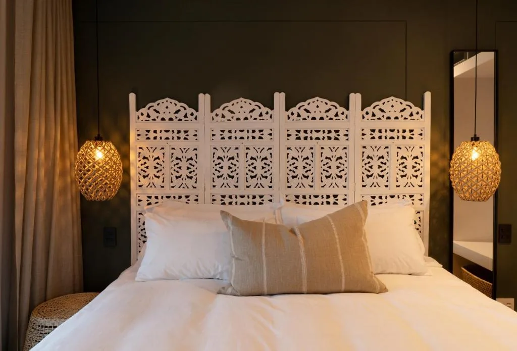 Elegant bedroom with ornate white headboard and golden pendant lighting