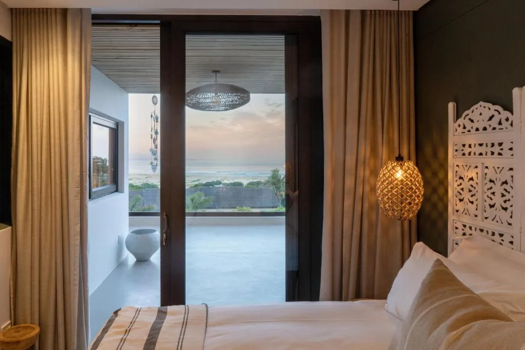 Bedroom with ocean view through open glass doors to deck