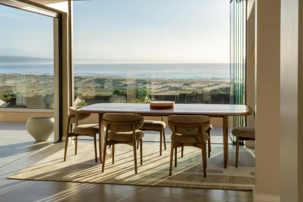 Modern dining table with ocean and beach views through large windows