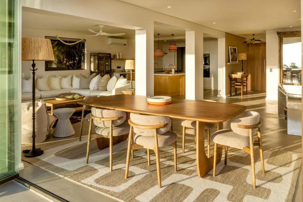 Modern dining area with wooden table and upholstered chairs, open-plan layout