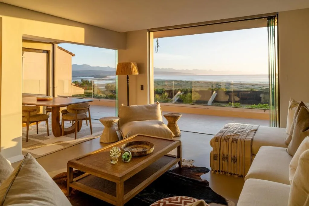 Bright lounge with sofas, wooden table, panoramic lagoon and mountain views