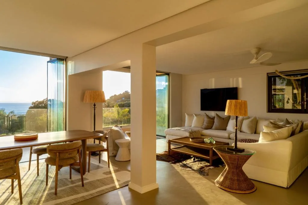 Spacious lounge with cream sofas, wooden furniture, ocean views through large windows