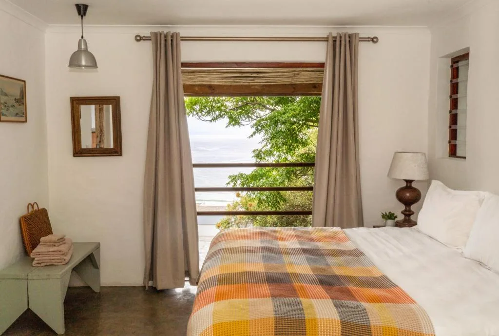 Bedroom with water view through large windows and patterned bedcover