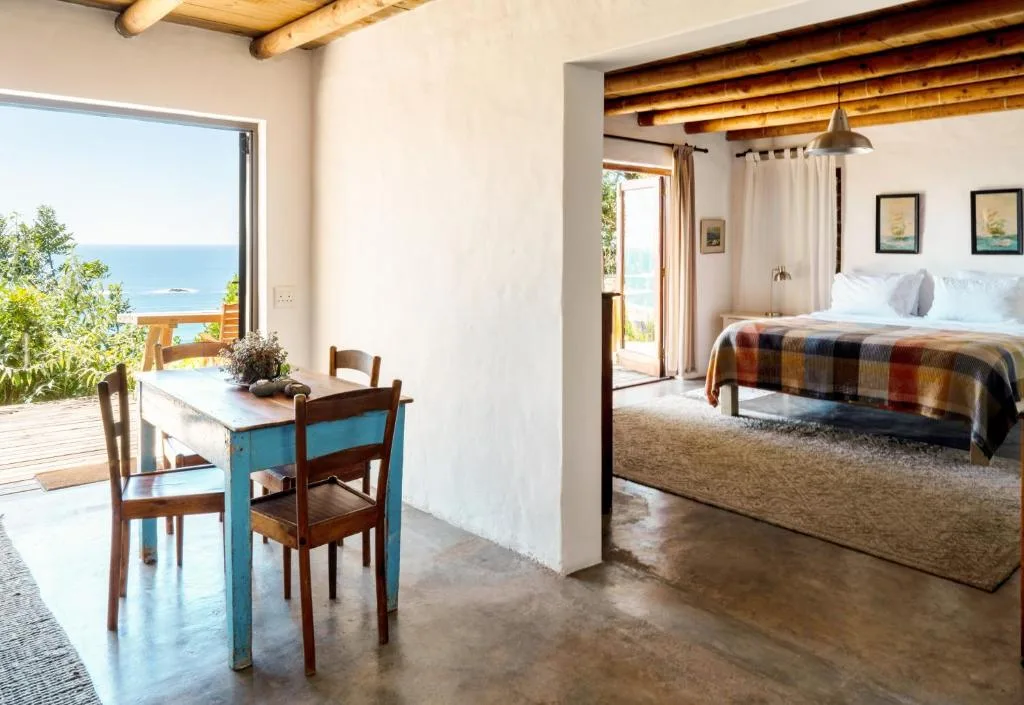 Spacious bedroom with ocean views through large glass doors and wooden beams