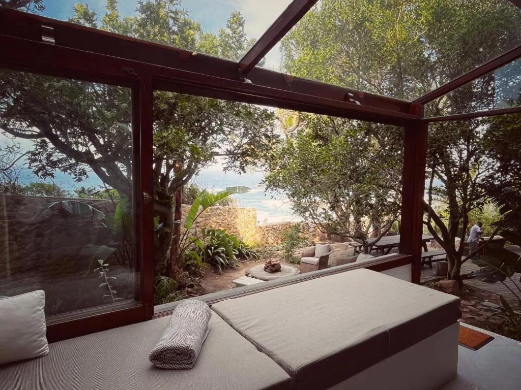 Covered wooden deck with lounge seating overlooking garden and ocean view