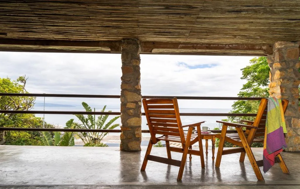 Covered deck with wooden chairs overlooking coastal landscape and sea views
