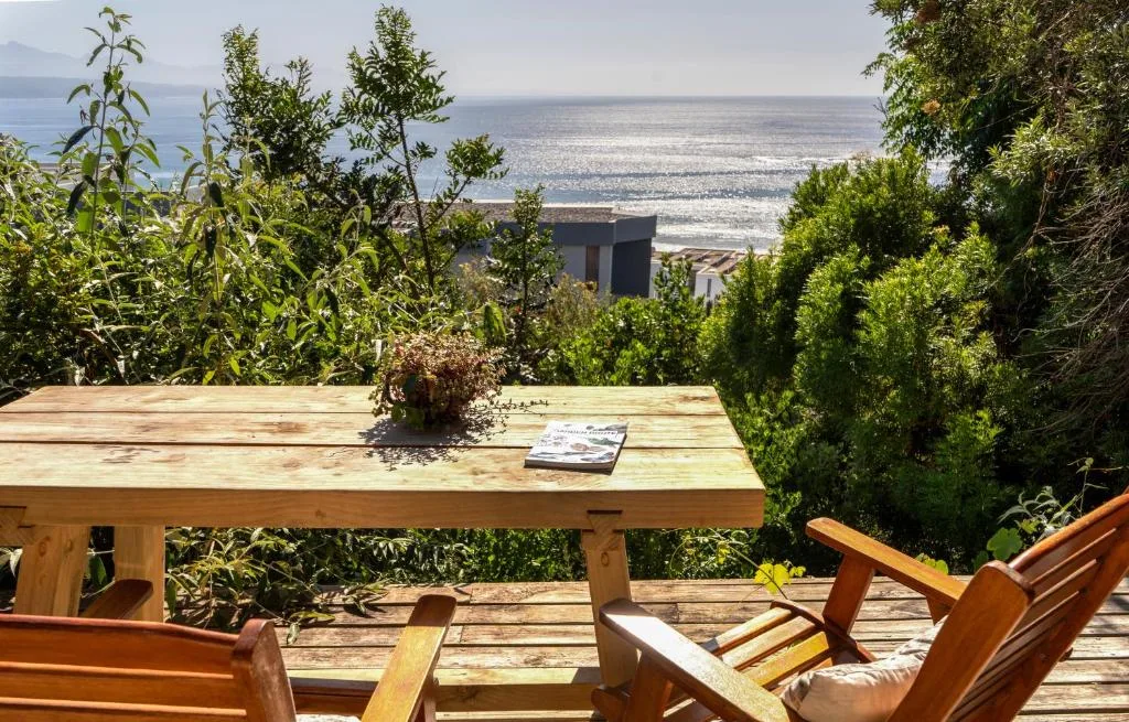Wooden deck with sea view, garden chairs, and coastal landscape beyond