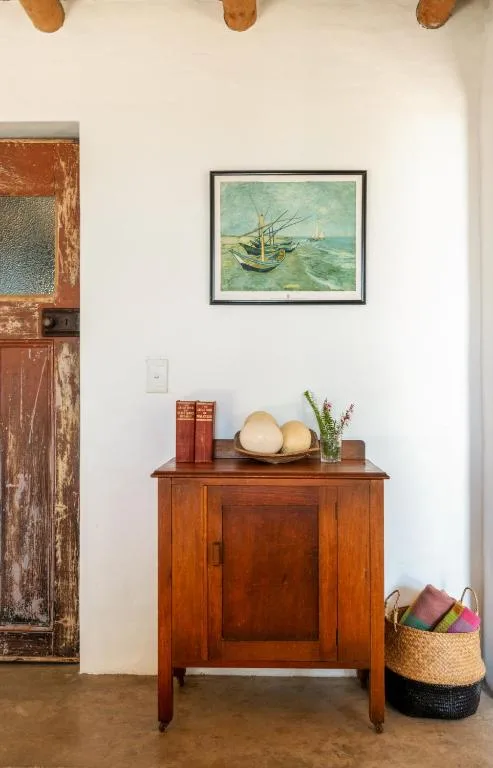 Wooden cabinet with decorative items and framed maritime artwork on wall