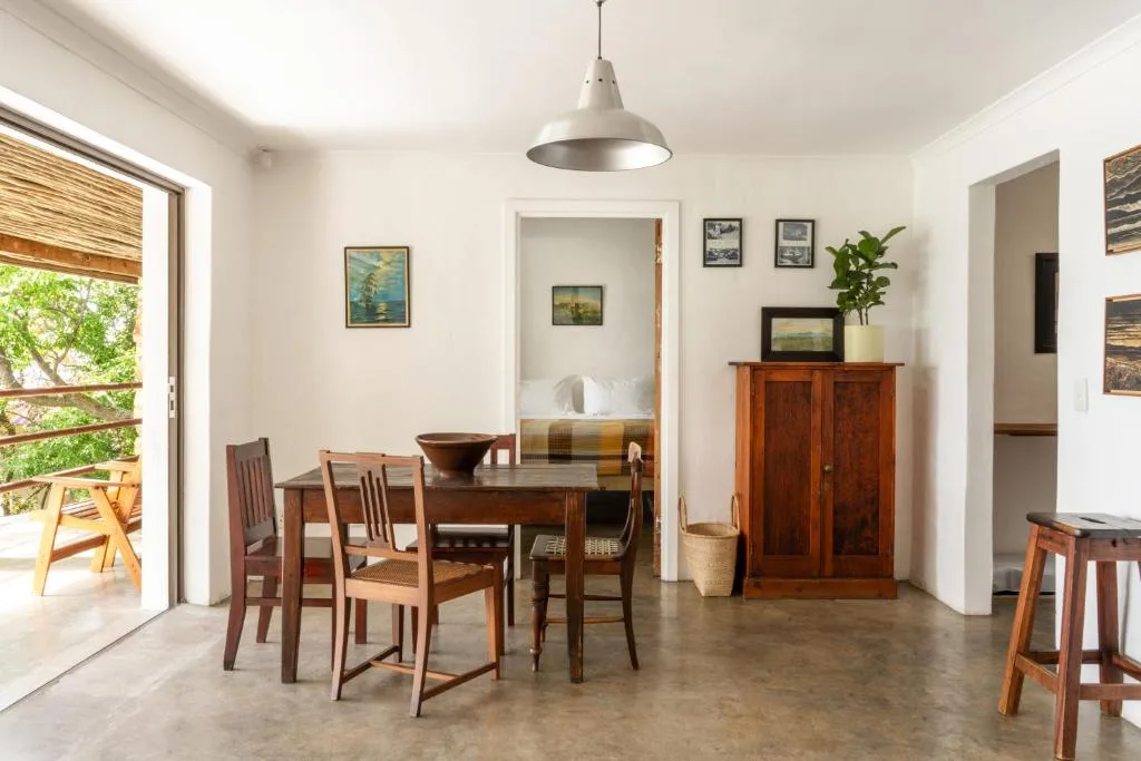 Open-plan dining area with wooden table, chairs, and pendant lighting overlooking deck
