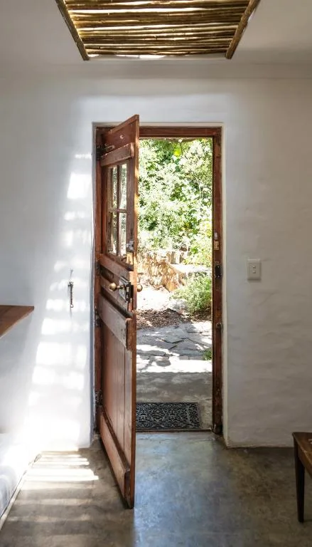 Wooden door opens to garden courtyard with lush green vegetation and stone pathway
