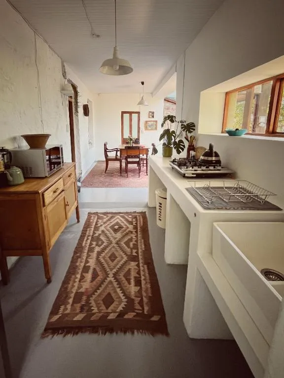 Galley kitchen with white appliances, wooden cabinetry, pendant lighting