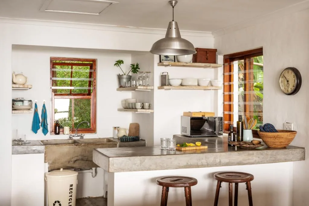 Modern kitchen with concrete counters, open shelving, and wooden stools