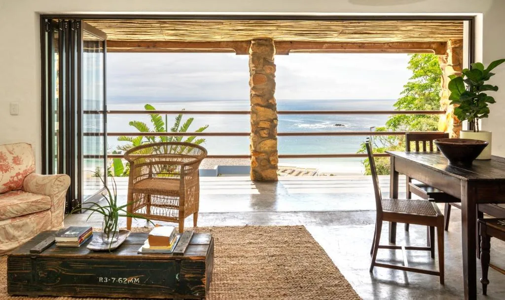 Spacious lounge with ocean views through large glass doors and coastal furnishings