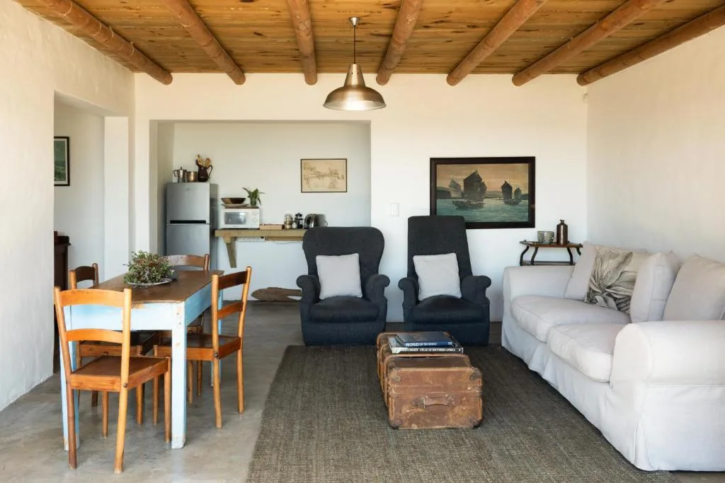 Open-plan living area with cream sofa, black armchairs, and wooden beam ceiling