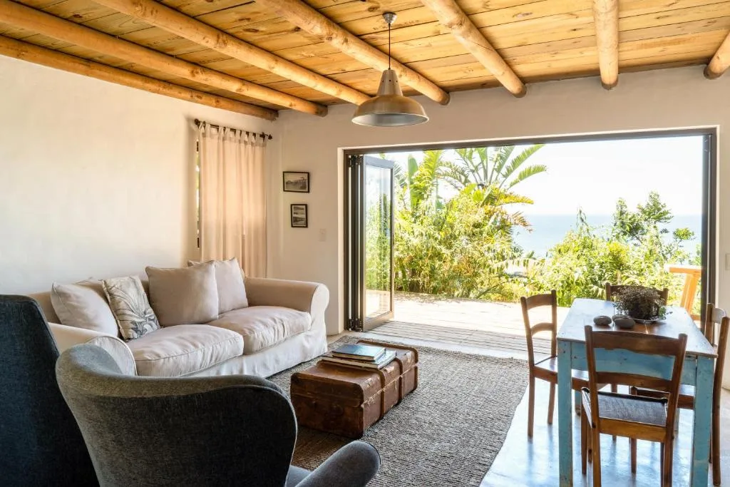 Spacious living room with sofa, armchair, and open deck views