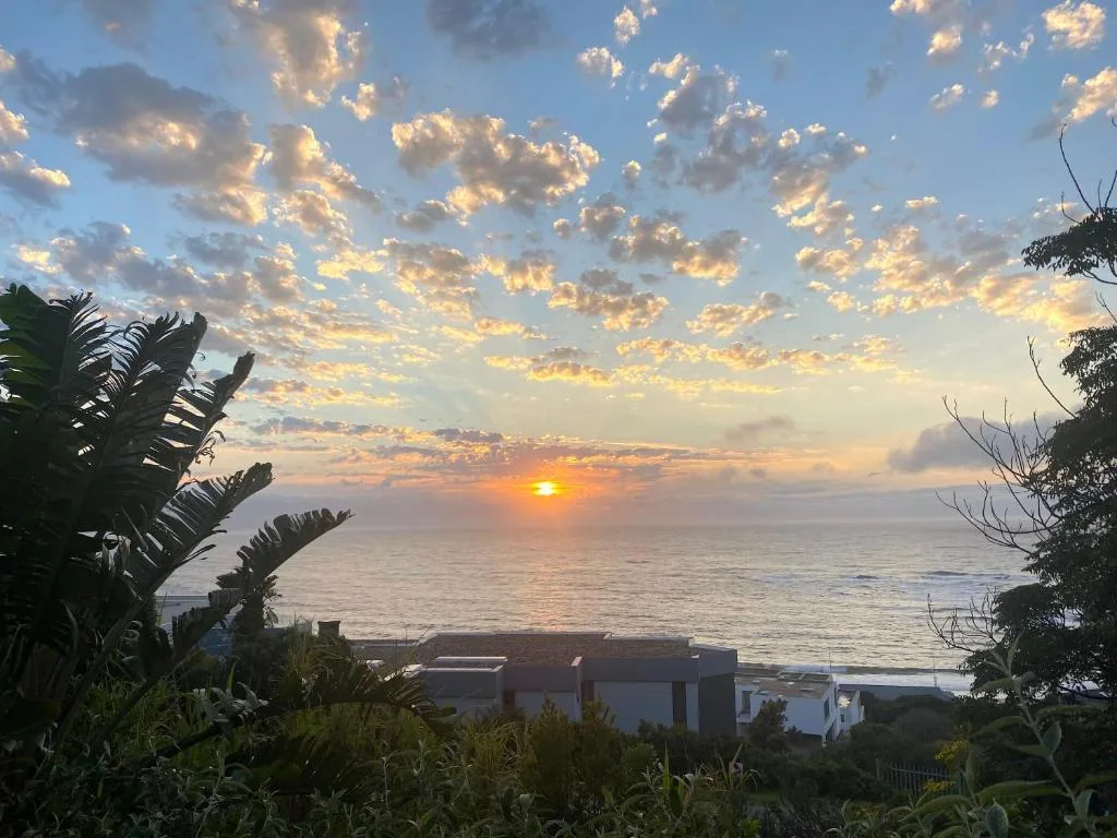 Sunset over the ocean with golden clouds and coastal property below