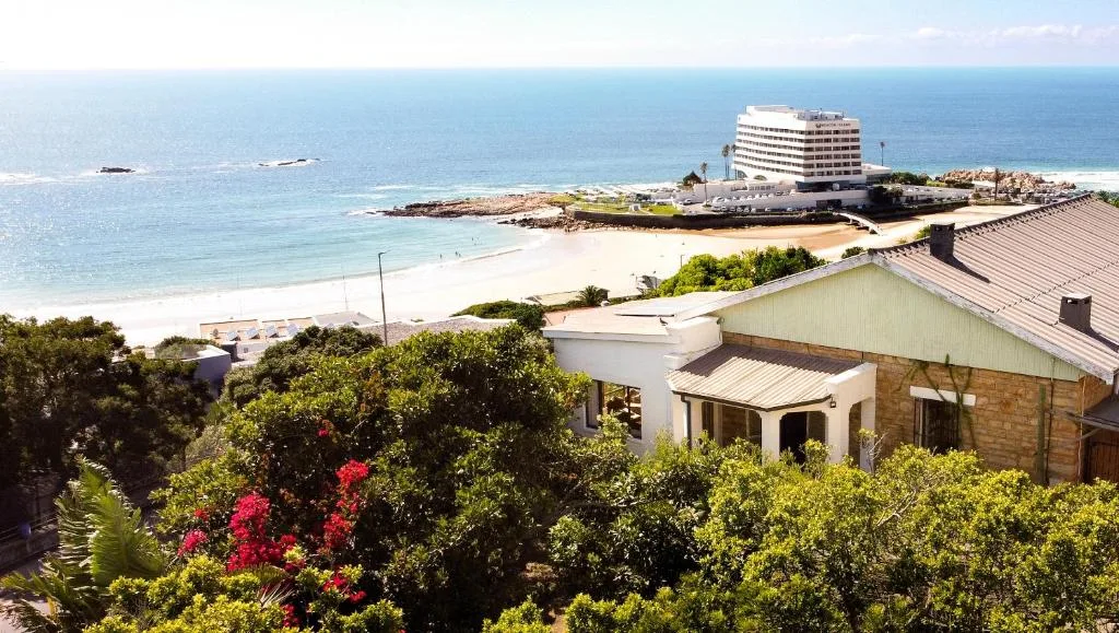 Beachfront view with white sandy beach, turquoise ocean, and coastal town architecture