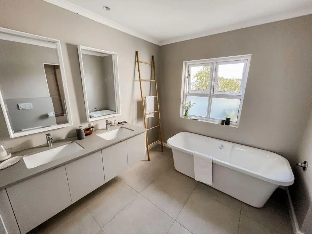 Modern bathroom with dual vanity sinks, large mirror, and freestanding bathtub
