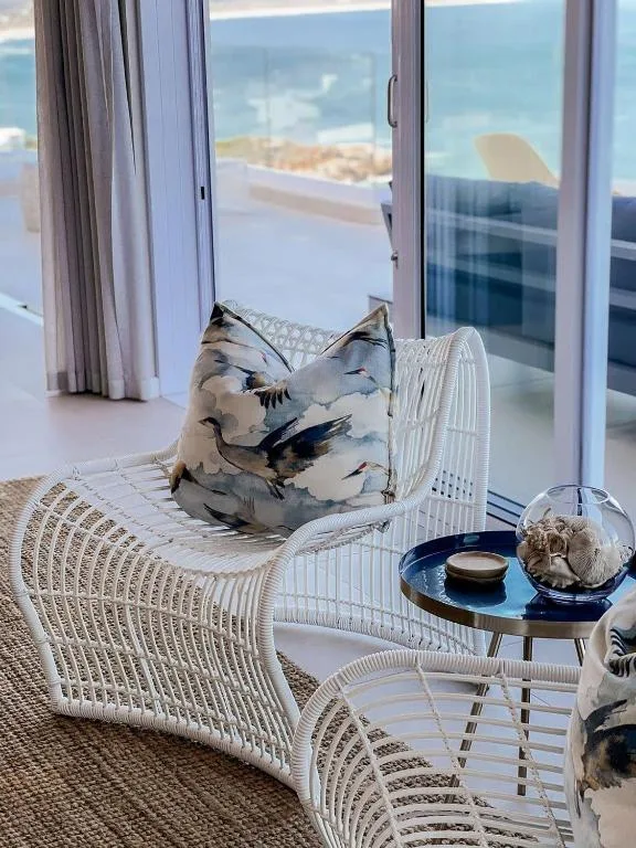 Modern white wicker seating area with ocean view through glass doors