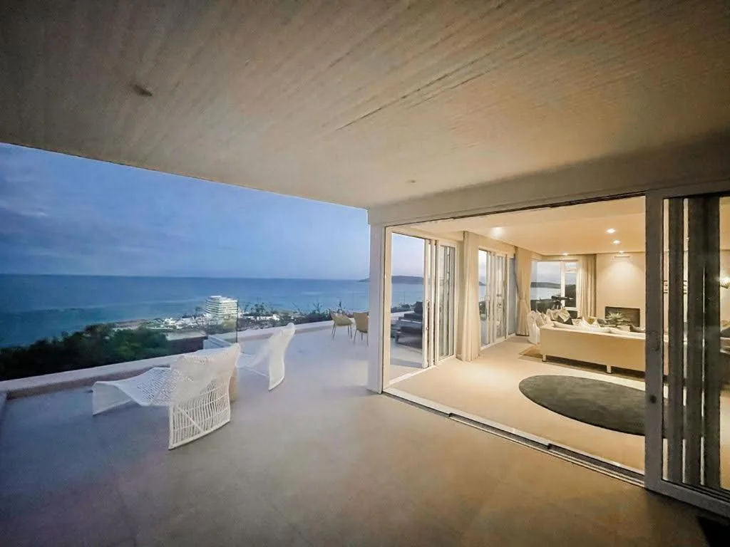 Spacious ocean-view deck with white chairs and sliding glass doors