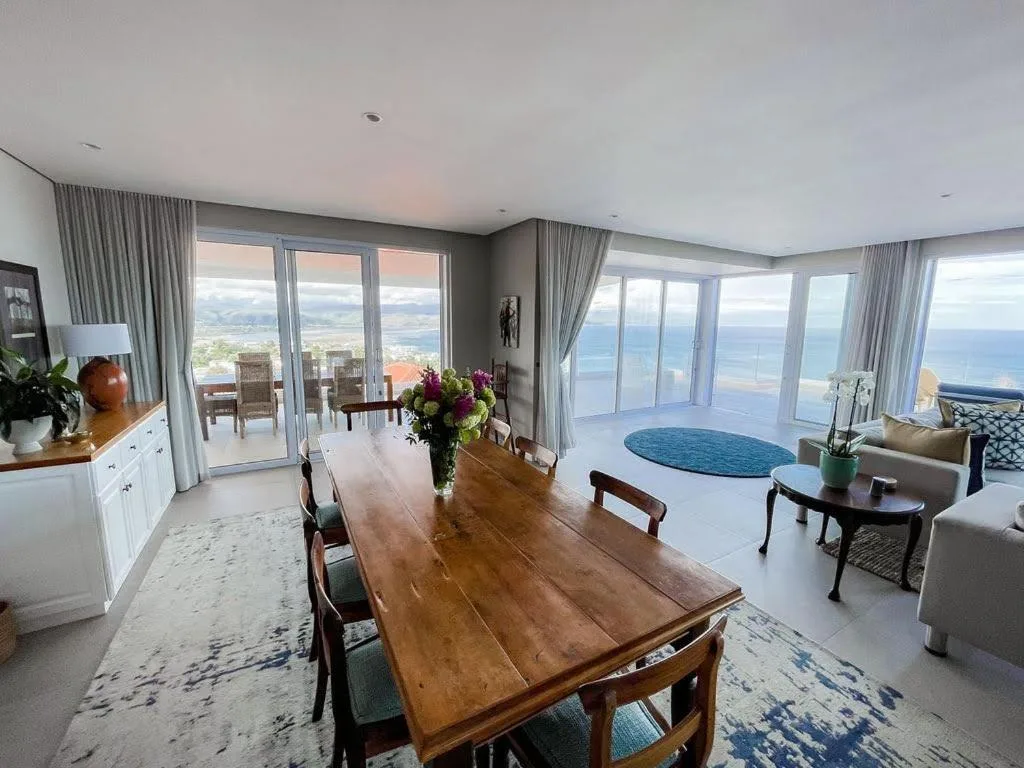 Open-plan dining area with wooden table overlooking panoramic ocean views
