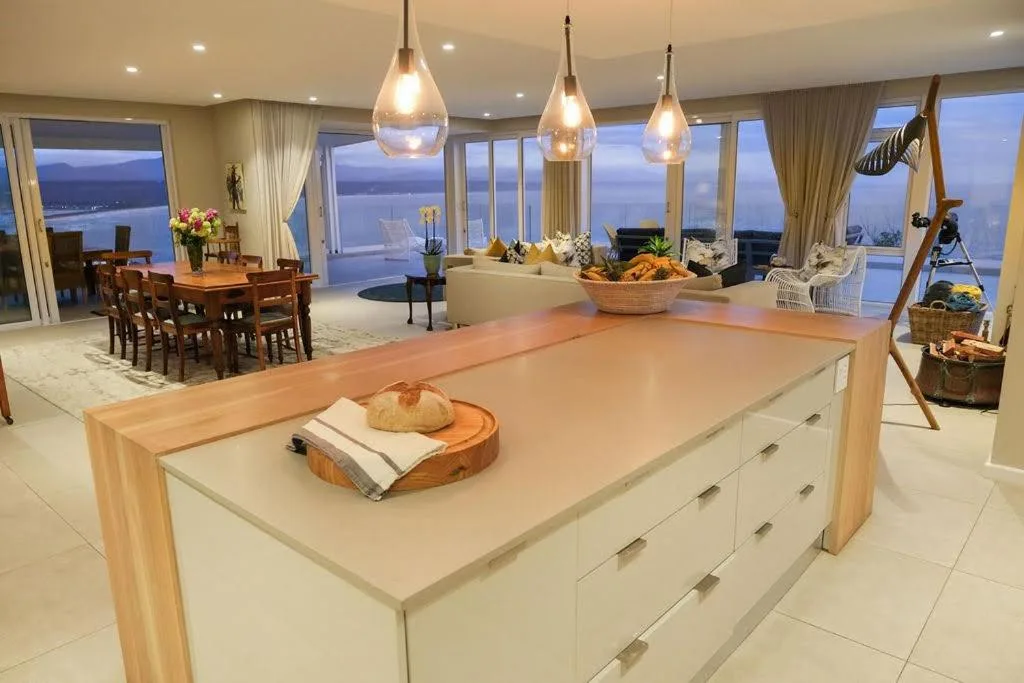 Modern kitchen with large island, pendant lighting, and panoramic ocean views