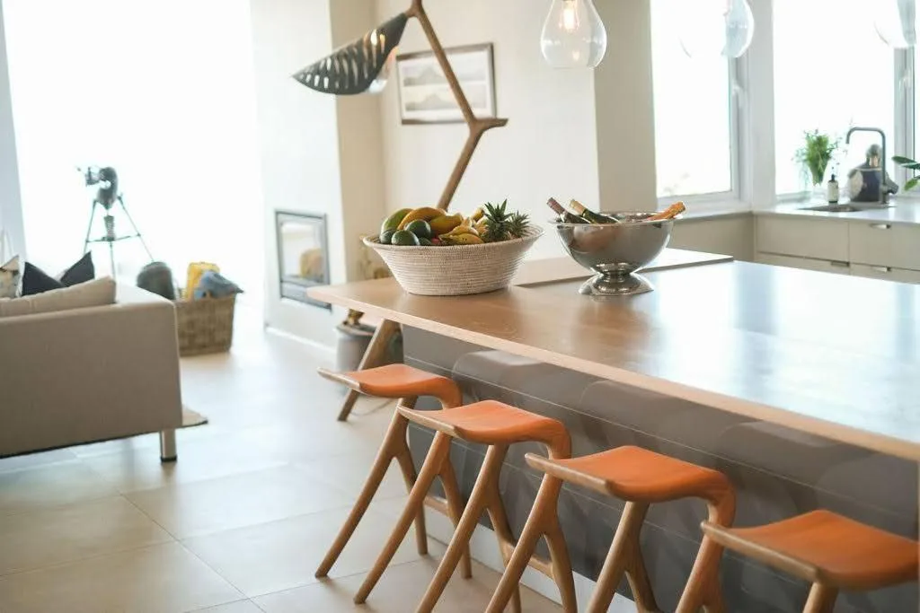 Modern kitchen with island counter, wooden chairs, and decorative bowls