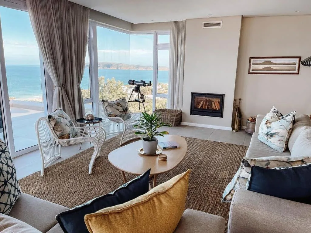 Spacious lounge with ocean views through floor-to-ceiling windows and coastal decor