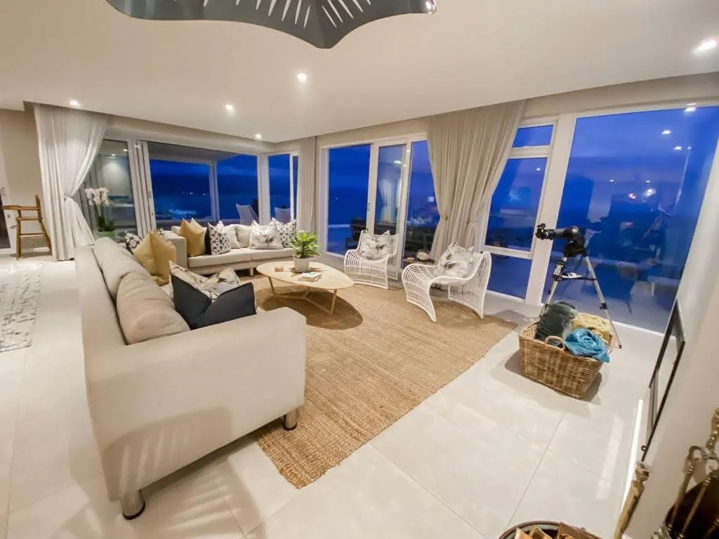 Modern lounge with cream sofas and panoramic blue evening views through floor-to-ceiling windows