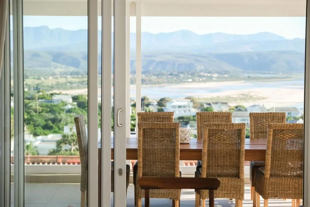 Panoramic lagoon and mountain vista from indoor seating area with wicker chairs
