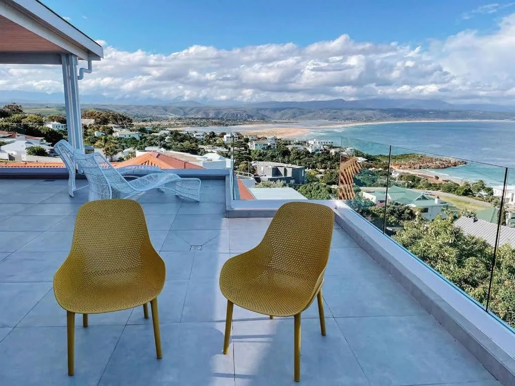 Coastal vista from deck chairs overlooking Plettenberg Bay beach and mountains