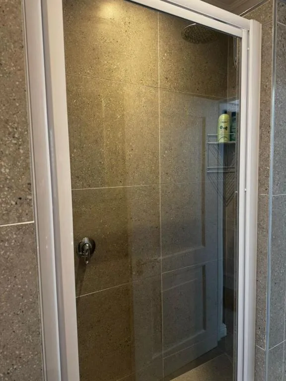 Walk-in shower with glass enclosure and bronze tile surround