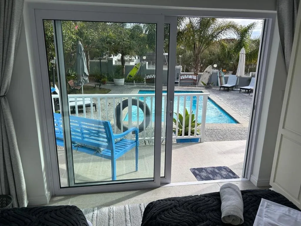 Bedroom with glass doors opening onto pool deck and tropical garden area
