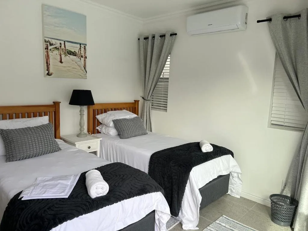 Bright bedroom with twin beds, wooden headboards, and beach-themed wall art