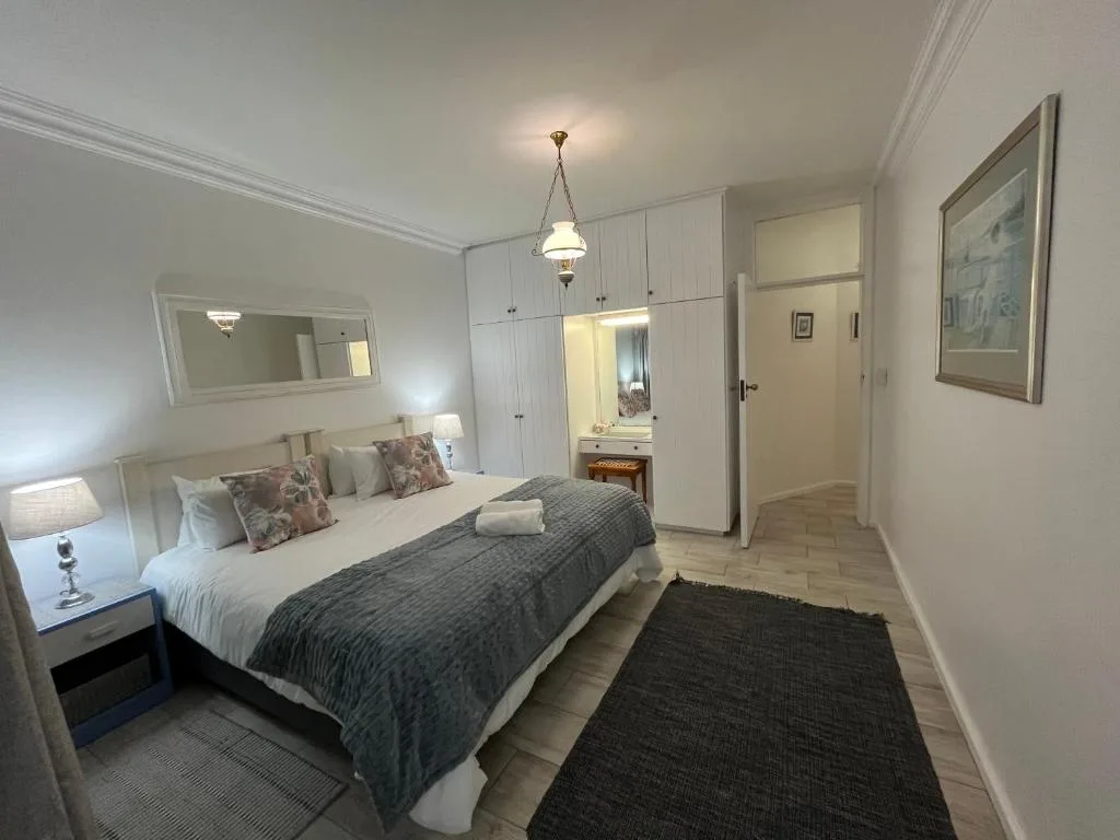 Spacious bedroom with queen bed, white cabinetry, and ensuite bathroom access
