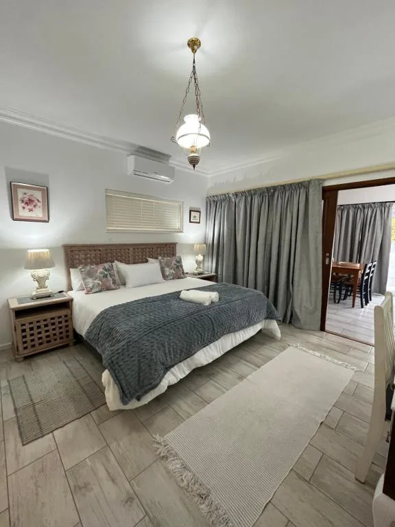 Spacious bedroom with queen bed, upholstered headboard, gray curtains