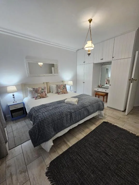 Bright bedroom with double bed, white built-in wardrobes, and vanity mirror