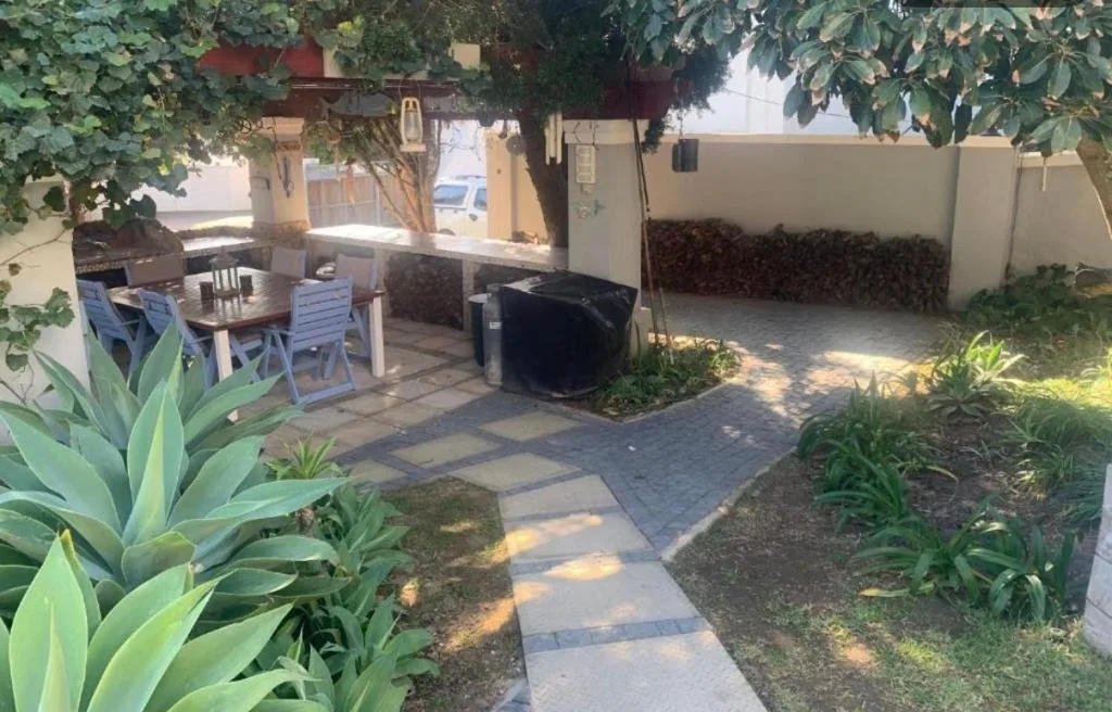Shaded patio with dining table, chairs, and lush garden surroundings