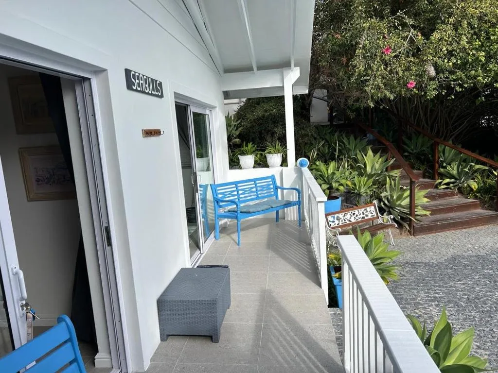 Covered patio with blue bench seating and lush garden surroundings
