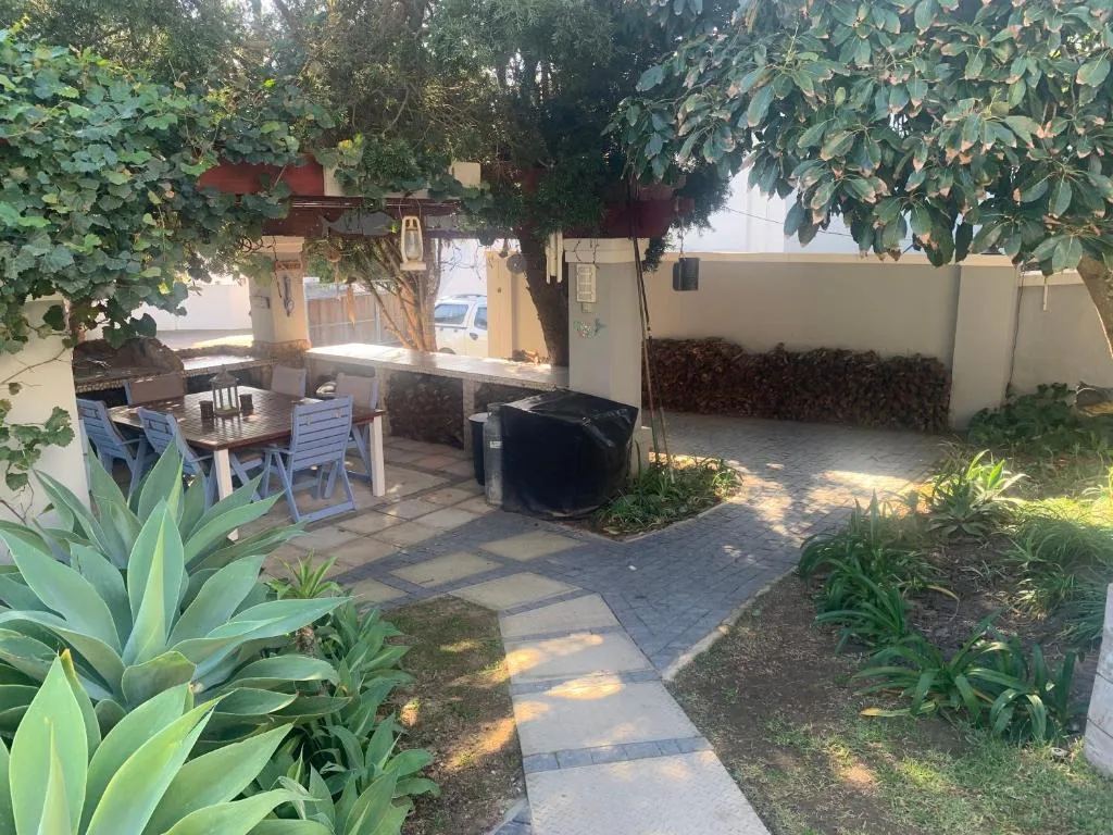 Shaded patio area with dining table, chairs, and built-in braai