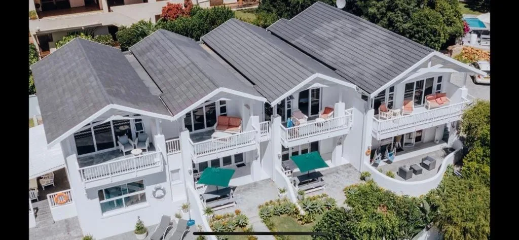 Aerial view of modern white multi-unit beachfront property with dark roofs