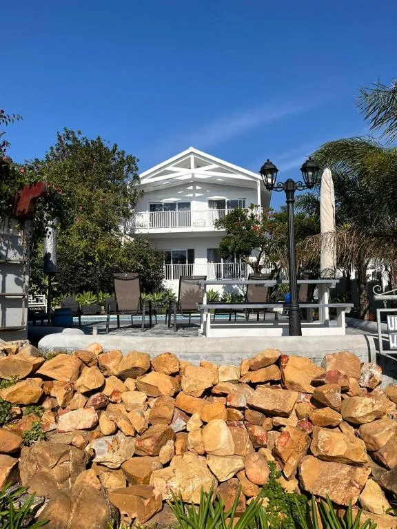 White two-story beachfront building with wraparound balconies and manicured gardens
