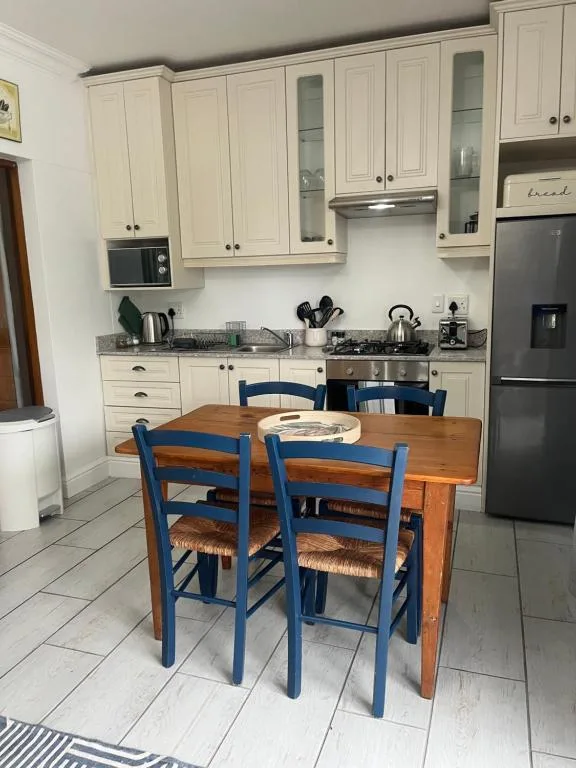 Cream cabinetry kitchen with dining table and blue chairs