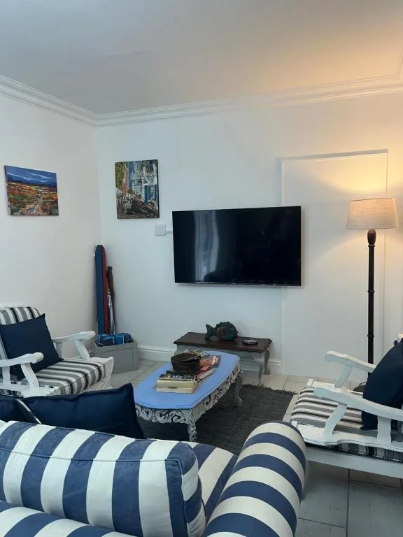 Bright living room with wall-mounted TV, striped navy furniture, and coastal decor