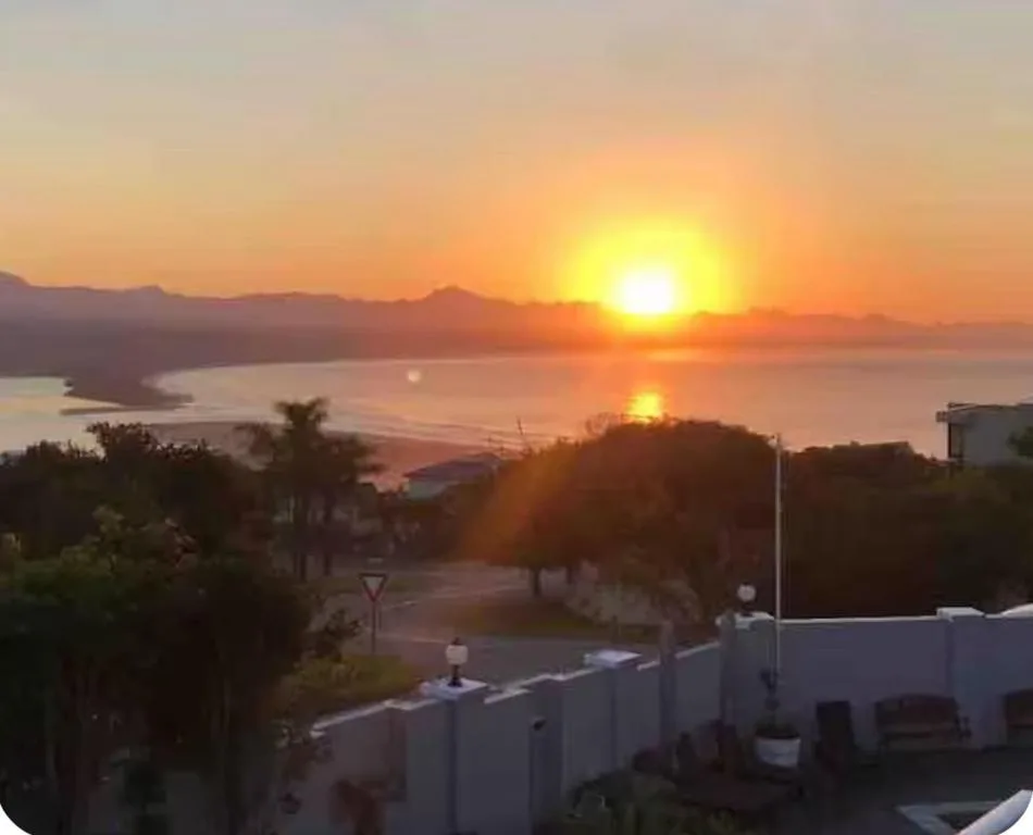Golden sunrise over lagoon with mountains and palm trees visible