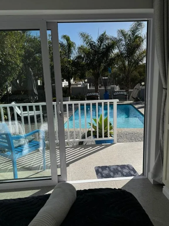 Pool and tropical garden viewed through open glass doors